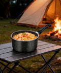 1.5 Quart Nonstick Saucepan With Detachable Handle And Swiss Granite Coating Small Multipurpose Pot For Induction Cooking PFOA Free Smokeless Pan For Quick Sauces And Everyday Meals on a camping table with pasta and shrimp, campfire background