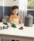 Child playing with 1 64 Scale Farm Playset With Grain Bin Includes Tractor Toys Skid Steer Farm Animal Figures And Fencing