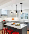 Three Pack Black Industrial Pendant Lights With Clear Glass Shades hanging over a kitchen island in modern farmhouse style.