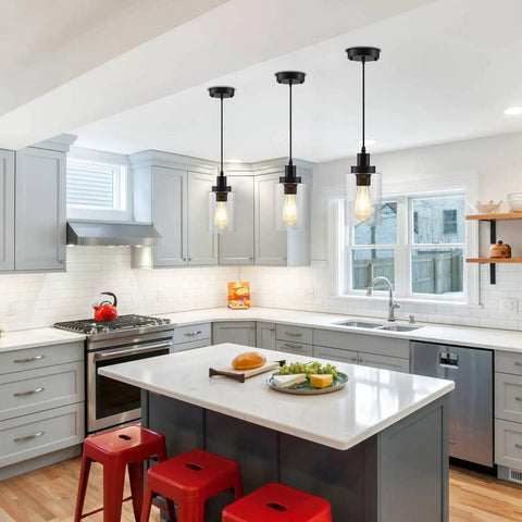 Three Pack Black Industrial Pendant Lights With Clear Glass Shades hanging over a kitchen island in modern farmhouse style.