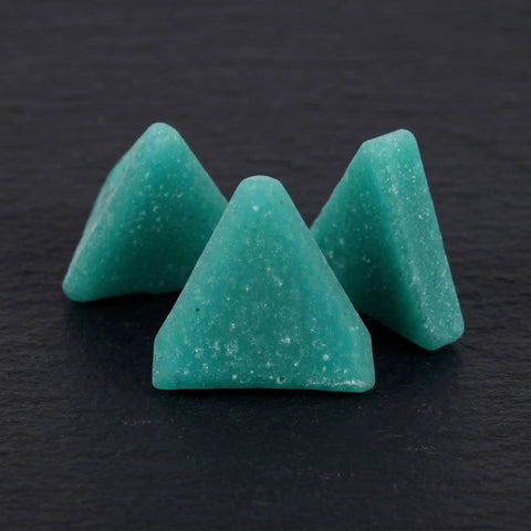 Close-up of blue triangular resin polishing media blocks with three usable sides for metal tumbling machines deburring and finishing.