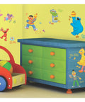 Sesame Street Peel And Stick Wall Decals For Kids Room on nursery walls with Elmo, Big Bird, and Cookie Monster near a toy chest.