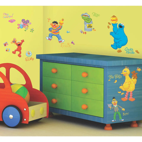 Sesame Street Peel And Stick Wall Decals For Kids Room on nursery walls with Elmo, Big Bird, and Cookie Monster near a toy chest.
