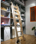 Wooden ladder leaning against shelves in room with sliding barn doors, part of Must Have Sliding Barn Door Kit With Rolling Ladder Hardware.