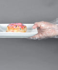 Hand wearing Clear Embossed Poly Gloves Large Ambidextrous For Food Handling holding donut plate