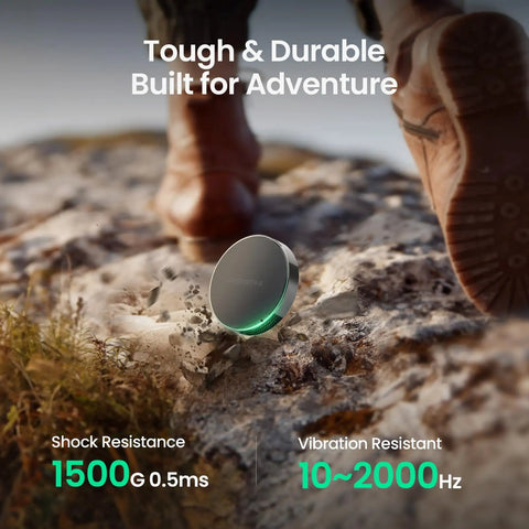 1TB Magnetic Portable SSD With USB C 3.2 Gen 2x2 Up To 2000 MB Per Second For Laptops iPhone 15 And 16 Tablets And USB C Devices Ultra Compact Go Anywhere External Solid State Drive Plug And Play Black resting on rocky terrain.