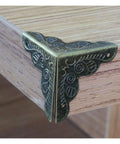 Antique Brass Corner Protectors For Wooden Boxes And Jewelry Cases Vintage Triangle Edge Guards With Screws on wooden surface.