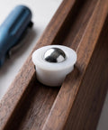 Close-up of 12pcs Steel Ball Transfer Casters with Nylon Housing, 0.7x0.5in, installed in wooden track with tool.