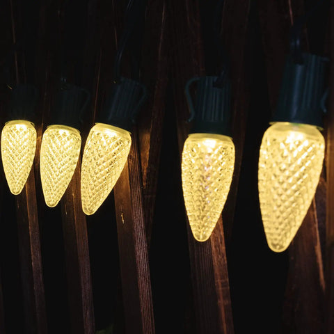 Close-up of illuminated outdoor globe string lights with shatterproof G40 bulbs hanging on a wooden fence for a cozy ambiance.