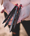 Close-up of hands holding Beefy 16 Pack 7075 Aluminum Tent Stakes 7.25 Inch Long Heavy Duty Ground Pegs Rust Resistant For Camping Canopy