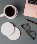 Dope White Marble Coasters Set Of 6 With Gold Brass Inlay For Luxury Aesthetic Modern Coffee Table Decor next to laptop and glasses