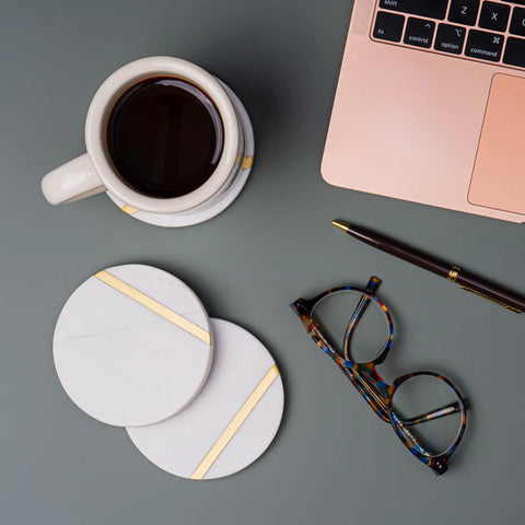 Dope White Marble Coasters Set Of 6 With Gold Brass Inlay For Luxury Aesthetic Modern Coffee Table Decor next to laptop and glasses