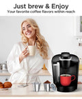 Smiling woman with coffee mug next to Keurig brewer and Universal Reusable Stainless Steel K Cups For Keurig 1.0 And 2.0 Brewers.
