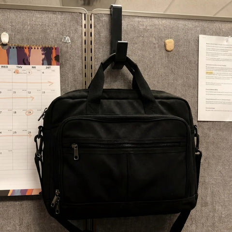 Black laptop bag hanging on 4 Pack Adjustable Cubicle Hooks For 1.8 To 3.5 Inch Panels And Walls, Plastic Coat Hooks.