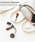 Mini Portable Bluetooth Speaker 5.0 Tiny But Mighty Sound For Outdoor And Indoor Use shown on table with bag and makeup brush