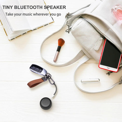Mini Portable Bluetooth Speaker 5.0 Tiny But Mighty Sound For Outdoor And Indoor Use shown on table with bag and makeup brush