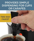 Close-up of a hand dispensing coffee using the two-way faucet on a 30 Cup Coffee Urn With Automatic Temperature Control And Fast Cup Per Minute Brewing Easy Cleanup In Basket Measuring Guide Ready Light Highly Polished Aluminum Silver Finish Ideal For Large Offices Events And Meetings.