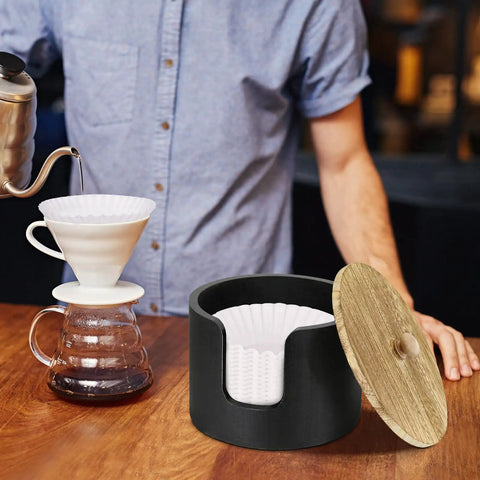 Coffee Filter Holder And Countertop Storage Jar With Lid For Easy Organization, wooden with filters next to pour-over coffee setup.