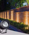 AC85‑265V IP65 Rotatable LED Flood Light (Green 25w) illuminating a brick wall in a landscaped garden.