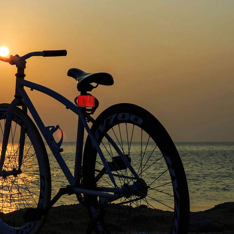 Bike with All In One Bike Front And Rear Reflectors Kit For Road Safety, rear red reflector visible during sunset ride by the sea.