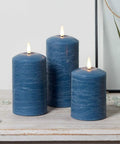 TruGlow Blue Distressed Wax Flameless LED Pillar Candles 3 Pack With Remote Control Battery Operated Timed On Off Lit Flicker on table