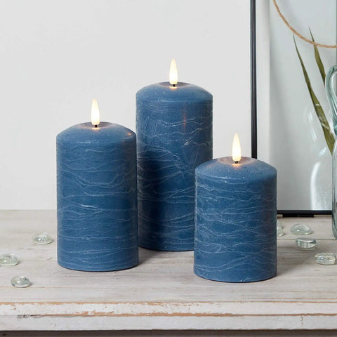 TruGlow Blue Distressed Wax Flameless LED Pillar Candles 3 Pack With Remote Control Battery Operated Timed On Off Lit Flicker on table