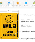 Two Pack Smile You're On Camera Video Surveillance Sign For Home And Business 10 X 7 Inch Heavy Duty 0.040 Inch Aluminum Indoor And Outdoor UV Protected And Reflective CCTV Security Sign showing specifications.