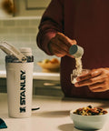 Rock Solid Leakproof Shaker Bottle With Connected Hinge Cap And Fast Flow Spout Built Tough For Gym Sessions And Trail Runs 20 Oz Tritan Protein Mixer That Truly Slaps Mixing Your Favorite Powders with protein powder being added.