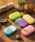Grab and Go Disposable Soap Sheets Set on a table with map, compass, and flowers, showcasing 5 colorful boxes of fragrant paper soap.
