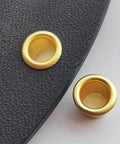 Close-up of gold brass eyelet rivets for holsters, 8.4mm size, showing the secure fit and quality build in black material.