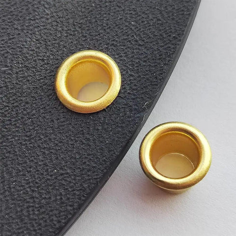 Close-up of gold brass eyelet rivets for holsters, 8.4mm size, showing the secure fit and quality build in black material.