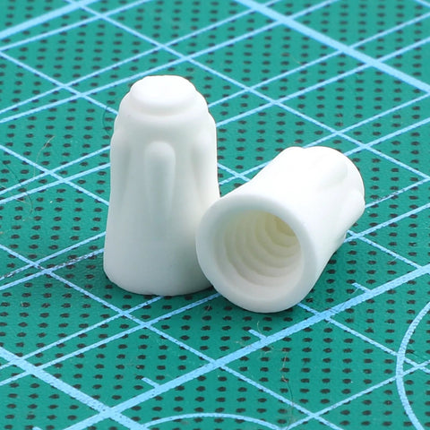 Porcelain wire connector caps, small white ceramic; front and side views with hollow interiors on a green cutting mat.
