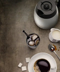 Two In One Coffee Maker With Ten Cup Thermal Carafe And Single Serve Brewer With Over Ice Function Fully Automatic Pod And K Cup Compatible For Four To Twelve Oz Brews Black And Stainless Finish, shown with iced and hot coffee, milk, and sugar cubes on a table.