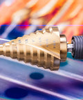 Titanium Nitride Coated HSS Step Drill Bit With One Quarter Inch Hex Shank Ten Imperial Step Sizes From One Quarter Inch To One And Three Eighths Inch Spiral Groove Double Flute 135 Degree Split Point For Sheet Metal Aluminum PVC Copper Acrylic NordWolf attached to a drill
