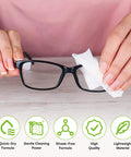 Care Touch eyeglass lens wipes being used to clean black-framed glasses with a white wipe