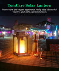 Lit Outdoor Solar Lantern With Realistic Flickering Flame on table, patio setting, decorative metal lantern, ambient lighting