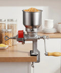 Manual Grain Mill With Low Hopper Hand Crank Cast Iron Grinder For Wheat Grains Spices Coffee Beans And Nuts Heavy Duty Table Clamp Dust Cover Non Electric Milling For Fresh Flavor At Home clamped on table with corn in hopper