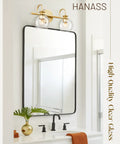 Gold Finish 15 Inch Two Light Vanity Light With Clear Globe Glass Shades above a mirror in a modern bathroom setting