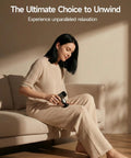 Woman using Mini Massage Gun With Heat For Deep Tissue Relief in living room, relaxing on sofa, showcasing ergonomic design for home use.