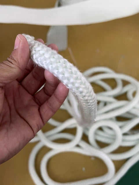 Person holding a white Graphite Impregnated Fiberglass Rope Seal Gasket For Wood Stoves 14mm By 2m White Replacement Heat Resistant Door Seal.