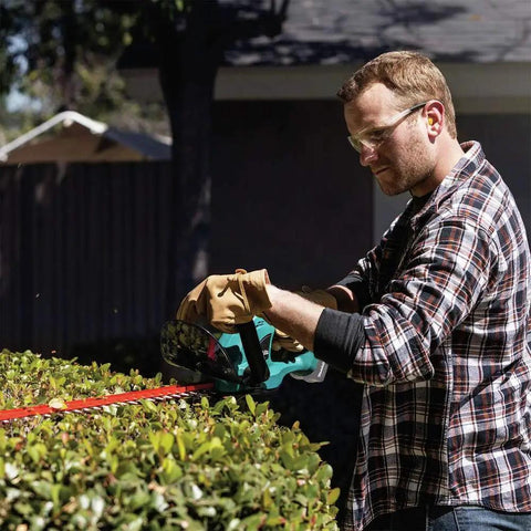 Man trimming hedge with 18V LXT Cordless Hedge Trimmer With 22-Inch Cut, Brushed Lithium-Ion Power, Tool Only, Renewed