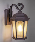 Outdoor Hex Wall Lantern Dusk To Dawn Sensor in Rustic Bronze Cast Aluminum with Seeded Glass Wet Location Rated Photocell Auto On At Night Durable Weatherproof Build With Moisture Blocking Rubber Washers and Five Year Warranty