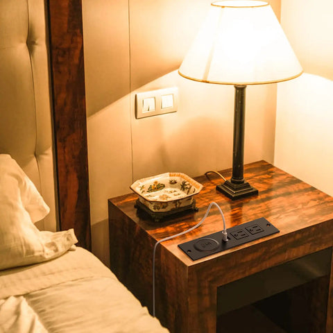 Recessed Power Strip With USB Ports And 10W Wireless Charging Station For Desk Or Table Two Outlets And Dual USB Ports UL Listed Furniture Power Hub For Sofa Table Cabinet Or Drawer With A 6.56 Foot Cord installed on a bedside table with lamp
