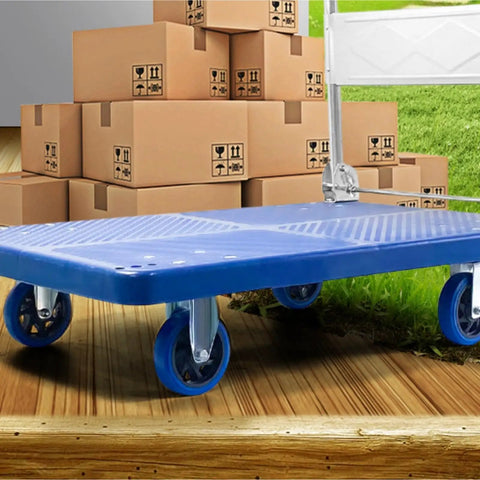 Heavy Duty Foldable Platform Cart With Smooth Glide Swivel Wheels And Self Leveling Balance Frame For Moving Couches Mattresses Or Toolbox Gear Haul Big Loads Like A Pro on wooden surface, surrounded by boxes.