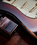 Octave Pedal OC-5 For Guitar And Bass With Mono And Poly Modes next to a brown electric guitar on a wooden surface