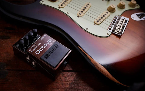 Octave Pedal OC-5 For Guitar And Bass With Mono And Poly Modes next to a brown electric guitar on a wooden surface