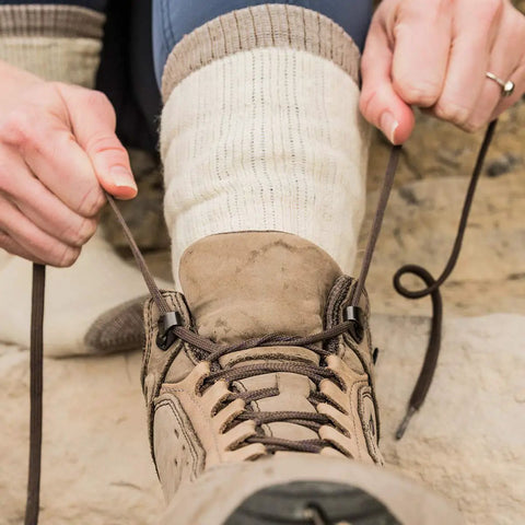 Person tying hiking boot over Merino Wool Hiking Socks With Cushioned Arch Support, Moisture Wicking, Tan Color, Extra Large
