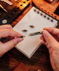 Hands holding Titanium Mini Infinity Mechanical Pencil Ultra Lightweight Compact Retractable Tip Portable Keychain Writing Tool