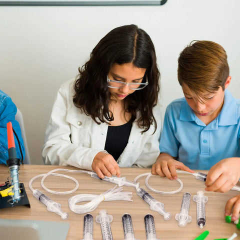 Children experimenting with Hands On Hydraulic And Pneumatic Kit With 48 10ml Syringes And 24 Clear 20 Inch Vinyl Tubes For DIY Projects Classroom Labs And Engineering Experiments on a table.
