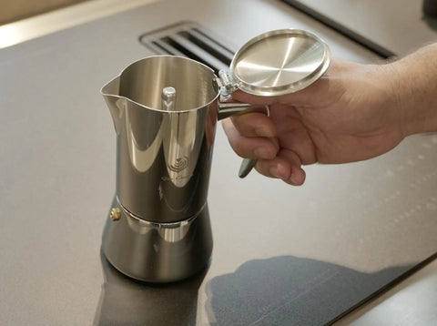 Hella Durable Stainless Steel Stovetop Espresso Maker For Rich Coffee Brews with open lid, held in hand, showing smooth finish.